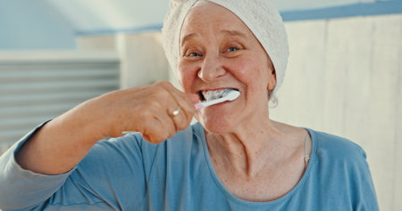 Hygiene, senior woman and brushing teeth in portrait for dental care, morning routine and fresh breath. Oral wellness, person and cleaning mouth in home for healthcare, getting ready and selfcareの写真素材