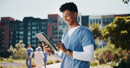 Happy man, nurse and research with tablet for internship, med school or healthcare course at campus. Male person, medical student or junior candidate with smile on technology for health study or appの写真素材
