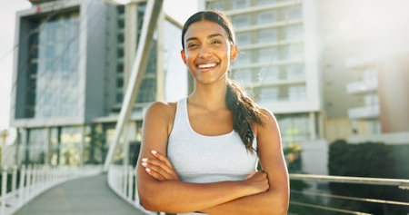 Portrait, fitness and woman in city, arms crossed and urban town with buildings, lens flare and wellness. Face, healthy athlete and person in street, confidence and runner with workout and trainingの写真素材