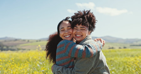 Friends, women and smile with hugging in field for travel adventure, reunion and bonding at rapeseed farm. Weekend trip, people and support in countryside for surprise connection and excited togetherの写真素材