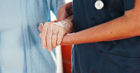 Holding hands, support and medical nurse with old person for healthcare, caregiver and empathy. Retirement, walking and elderly care with closeup of people in nursing home for trust and helpの写真素材