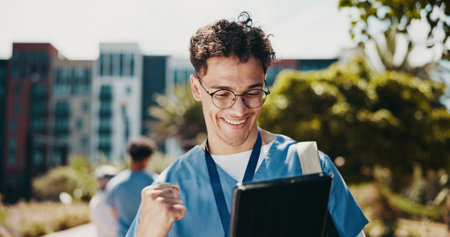 Happy man, nurse or medical student with tablet for winning, achievement or good news at med school. Male person, healthcare intern or candidate with smile on technology for results, success or passの写真素材