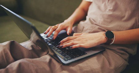 Hands, typing and laptop with woman on sofa for social media, reading blog and streaming service. Networking, email and search with closeup of person in living room at home for online and websiteの写真素材