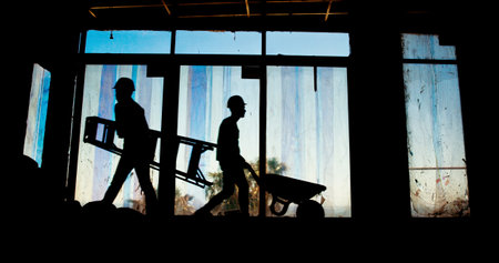 People, teamwork and silhouette on construction site for urban development, engineering or renovation. Industry, shadow or project with productivity, process or architecture with real estate or toolsの写真素材
