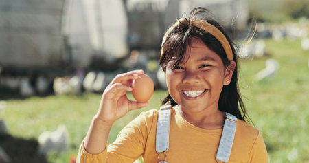 Girl, child and egg at chicken farm for portrait, smile and outdoor with learning in countryside. Kid, happy and excited on field with poultry, birds and food at free range agriculture in Malaysiaの写真素材