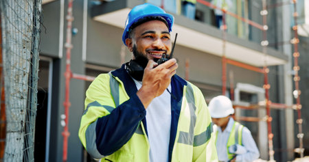 Construction site, engineering and man with radio, conversation and building development. Employees, coworkers and management for renovation, productivity and safety with helmet, talk or architectureの写真素材