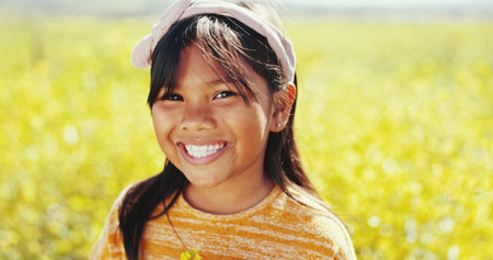 Portrait, flowers and nature with child in field for environment, growth and sustainability. Freedom, wellness and meadow with young girl in countryside garden for spring season, park and vacationの写真素材