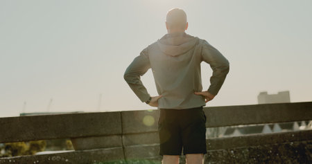 Sky, back and fitness for person, bridge and routine for athlete, fresh air and healthy for marathon. Outdoor, summer and runner in morning, lens flare and wellness with jog, city and workoutの写真素材