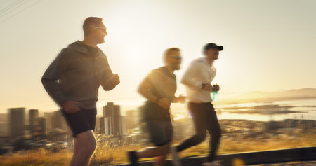 Men, fitness and running with sunset or speed for exercise or outdoor training together on mountain. Active, male people or runners with motion blur for sprint, race or health and wellness in natureの写真素材