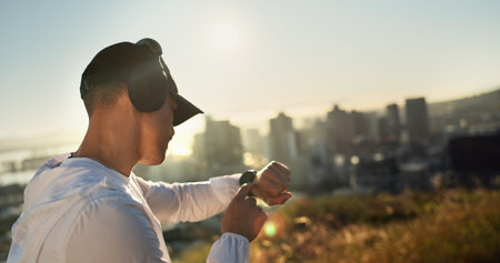 Man, headphones and smart watch outdoor for fitness, music and streaming radio with app, audio or workout. Male person, time and training for challenge, biometric and morning run with health trackerの写真素材