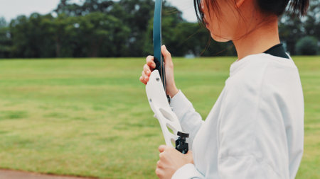Girl, bow or hands of archer for sports training, field or preparing for competition, equipment or game. Archery, athlete or shooting range in tournament with skills, challenge and practice in Japanの写真素材
