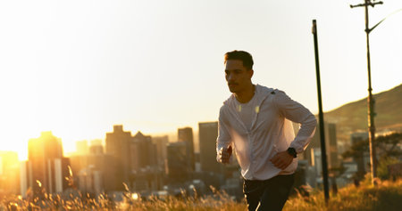 Man, runner and sunset with exercise, training and city for fitness or cardio workout. Athlete, person and countryside on mountain for wellness, health and summer marathon performance or enduranceの写真素材