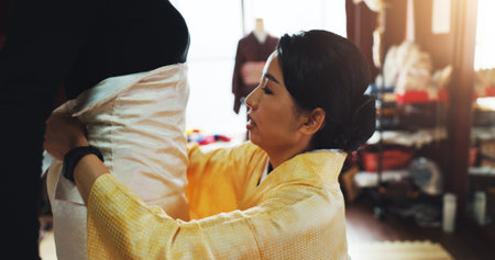 Asian woman, fashion designer and size with garment for kimono, style or dress maker at boutique. Japan, female person or tailor and seamstress checking waist with fabric for clothing design at storeの写真素材