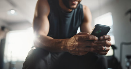 Fitness, gym and hands of man with phone on break for social media, internet and online message. Athlete, health and person with smartphone for mobile app for exercise, training and workout progressの写真素材