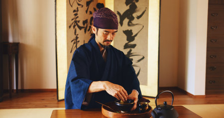 Man, relax and tea ceremony for zen, culture and matcha in home with preparation in Japan. Male person, ritual and bowl for mindfulness, tradition and buddhism with spiritual, respect and harmonyの写真素材