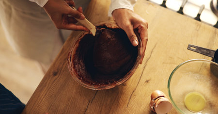 Hands, person and chocolate mixture for baking in bowl for Christmas dessert, cake and meal prep in kitchen. Closeup, baker and chef at home with culinary skills or talent for snack and cupcakesの写真素材