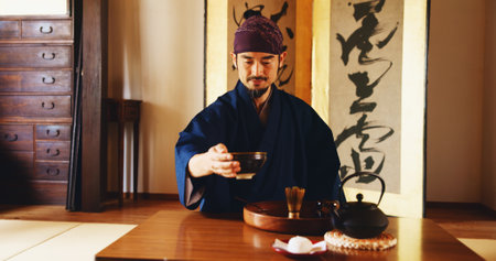 Man, relax and tea ceremony in Japan for tradition, culture and matcha in home with preparation. Male person, ritual and bowl for mindfulness, zen and buddhism with spiritual, respect and harmonyの写真素材