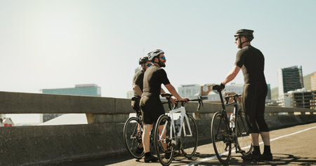 Bicycle, city and conversation with sports people outdoor together for hobby, recreation or team building. Break, cycling and partnership with athlete friends in urban town for exercise or fitnessの写真素材