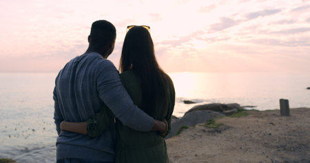 Sunset, beach and couple in embrace on romantic date, holiday adventure or sightseeing from back....
