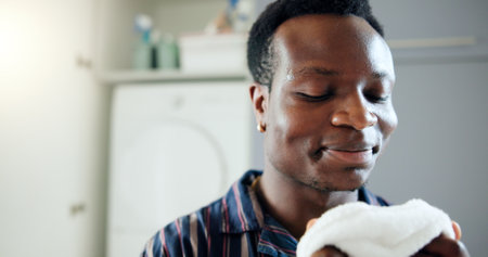 Laundry, black man and smell for clean blanket, fresh scent and linen fragrance for happy memory in home. Housekeeping, African person and smile with textile aroma for comfort, nostalgia and hygieneの写真素材