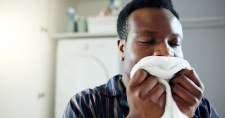 Laundry, black man and smell in home for clean blanket, fresh scent and linen fragrance for happy memory. Housekeeping, African person and smile with textile aroma for comfort, nostalgia and hygieneの写真素材