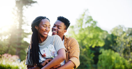 Black couple, romance and park with hug on vacation in forest with love, care and bonding together. Smile, trust and happy people with travel, marriage and commitment outdoor on weekend trip or dateの写真素材