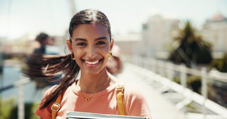 Portrait, happy student and woman outdoor with wind for learning, education and university scholarship. Smile, face and girl with textbook at college campus for knowledge, future opportunity or studyの写真素材