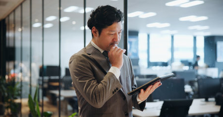 Japan, business and man with tablet, thinking and internet with stock market, connection and network. Asian person, accountant and employee in modern office, communication and digital app for emailの写真素材