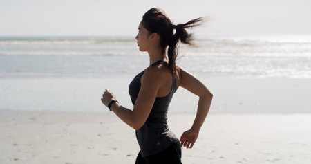 Fitness, woman and running on beach for training, wellness activity or cardio exercise with space. Girl, runner and workout challenge at ocean for marathon endurance, healthy body and energy in Spainの写真素材
