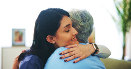 Caregiver, hug and senior woman on sofa with smile for support, kindness and empathy in retirement. People, embrace and elderly patient with care, solidarity and together in lounge at nursing homeの写真素材