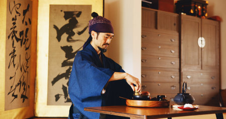 Man, preparation and tea ceremony in Japan for tradition, culture and matcha in home with relax. Male person, ritual and bowl for mindfulness, zen and buddhism with spiritual, respect and harmonyの写真素材