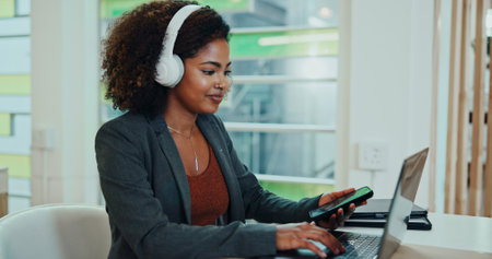 Business, woman and smile on laptop with headphones at office for project deadline as website designer. Female person, employee and happy on internet or online for creative ideas on radio and podcastの写真素材