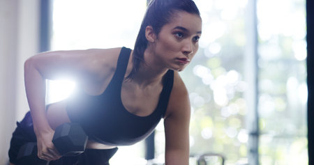 Arm, dumbbell and exercise with woman in gym for physical improvement or strength training. Health, power and triceps workout with confident person weightlifting for concentration or fitness routineの写真素材
