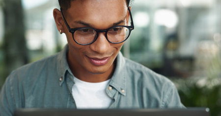 Reading, laptop and glasses with business man in office for journalist, article proofreading and editor. Email, news and report with employee in startup agency for entrepreneur, network and projectの写真素材