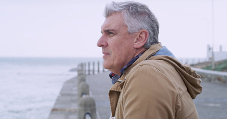 Thinking, relax and memory with old man at beach for reflection, mental health and inspiration. Perspective, vision and mindset with senior person contemplating outdoors for decision and breakの写真素材