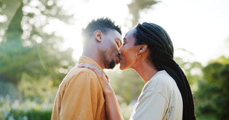 Kiss, love and black couple in nature in morning together for bonding, relationship and affection outdoors. Relax, dating and man and woman outdoors for romance, holiday and commitment on weekendの写真素材
