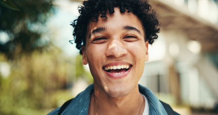 Portrait, happy student and man laugh at university outdoor for learning, education or scholarship at park. Smile, face or funny person at college campus or excited for future opportunity in Portugalの写真素材