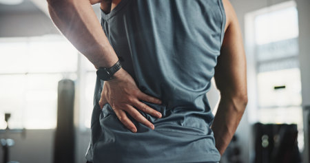 Man, hands and back pain with injury at gym for muscle tension, workout accident or sprain. Closeup,...