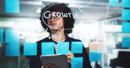Businessman, night or thinking with tablet or mindmap for schedule planning, brainstorming or strategy at office. Man, employee or corporate growth with sticky notes for company agenda on glass boardの写真素材