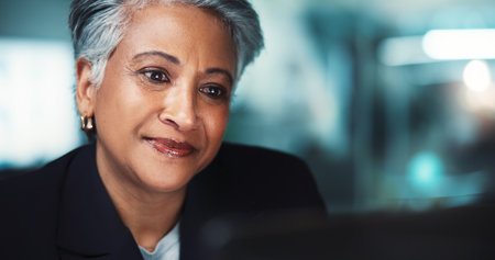 Night, reading and mature woman in accounting for finance management, business or budget review. Accountant, laptop or profit growth report in office for audit deadline, tax compliance or researchの写真素材