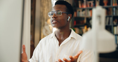 Video call, coaching and black businessman on computer in virtual meeting for discussion or online briefing. Explain, earphones or consultant in webinar for advice, remote work and talking in homeの写真素材