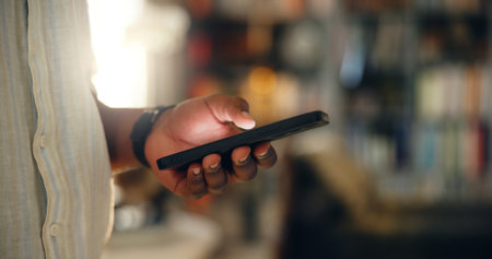 Person, hands and research with phone at library for knowledge, information or online app. Closeup, researcher or student with mobile smartphone for study, web search or communication at book storeの写真素材