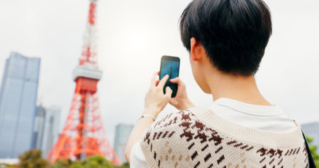 Tourism, photography and person with smartphone, city and capture of landmark, screen and content creation. Outdoor, influencer and tourist with mobile, display and picture of Tokyo Tower in Japanの写真素材