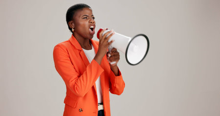 Black woman, angry and megaphone in studio for announcement, opinion and protest. Person, frustrated or loud speaker on white background for motivational speech, vote and activism for gender equalityの写真素材