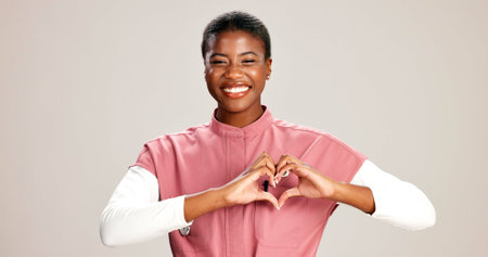 Doctor, woman and portrait with heart hands on studio background for healthcare support and kindness. Mockup space, black person and love sign for medical trust and thank you for pediatric serviceの写真素材