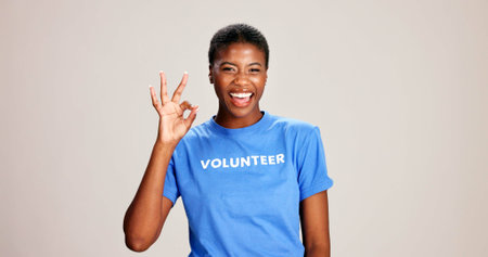 OK, sign and volunteer woman with portrait on studio background for NGO project success and approval. Black person, happy and perfect emoji on mockup space for charity support and community serviceの写真素材