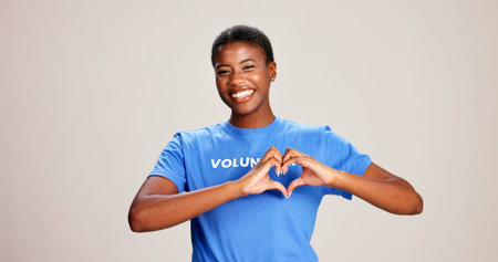 Volunteer, woman and portrait with heart hands on studio background for charity support and kindness. Mockup space, black person and love sign for NGO project care and thank you for community serviceの写真素材