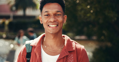 Portrait, happy student and man at university outdoor for learning, education and scholarship at park. Smile, face and confident person at college campus for studying, travel and pupil at academyの写真素材