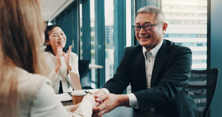 Cooperation, handshake and business people in meeting, teamwork and promotion with bonus. Japan, group and employees with celebration, collaboration and partnership with success, deal or negotiationの写真素材