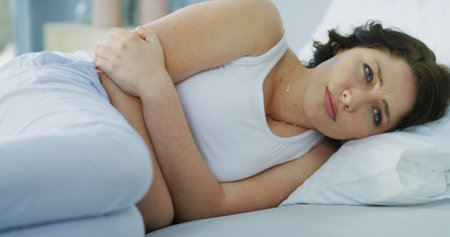 Sad, woman and thinking on bed at house with depression, mental health and insomnia anxiety. Girl, thoughts and remember past with trauma challenge, broken heart and sleep apnea for loneliness regretの写真素材